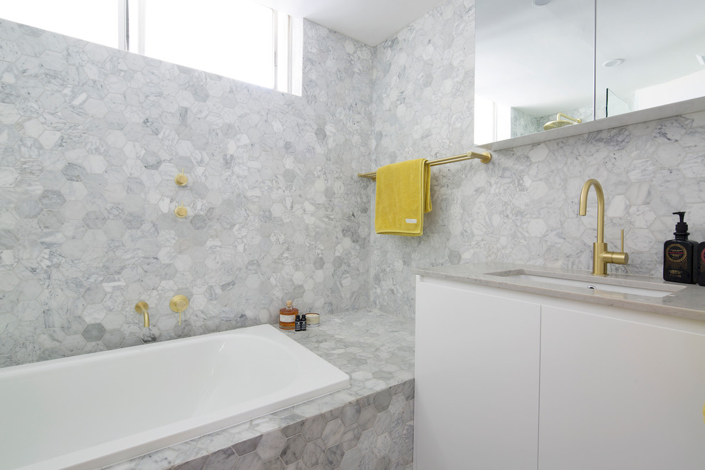 Bild på ett funkis grå grått badrum med dusch, med släta luckor, vita skåp, ett platsbyggt badkar, en dusch/badkar-kombination, grå kakel, vit kakel, marmorkakel, grå väggar, ett undermonterad handfat och med dusch som är öppen