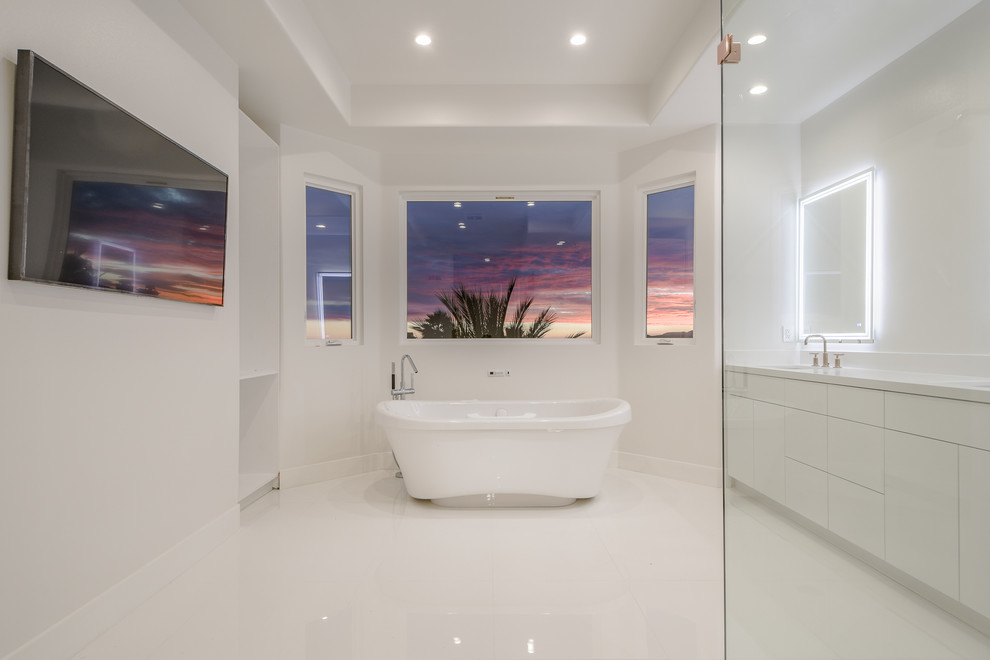 Photo of a large contemporary ensuite bathroom in Los Angeles with flat-panel cabinets, white cabinets, a freestanding bath, a corner shower, grey tiles, white tiles, marble tiles, white walls, a submerged sink, engineered stone worktops, white floors, an open shower and white worktops.