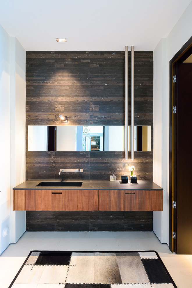 Пример оригинального дизайна: ванная комната в современном стиле с плоскими фасадами, фасадами цвета дерева среднего тона, черными стенами и монолитной раковиной