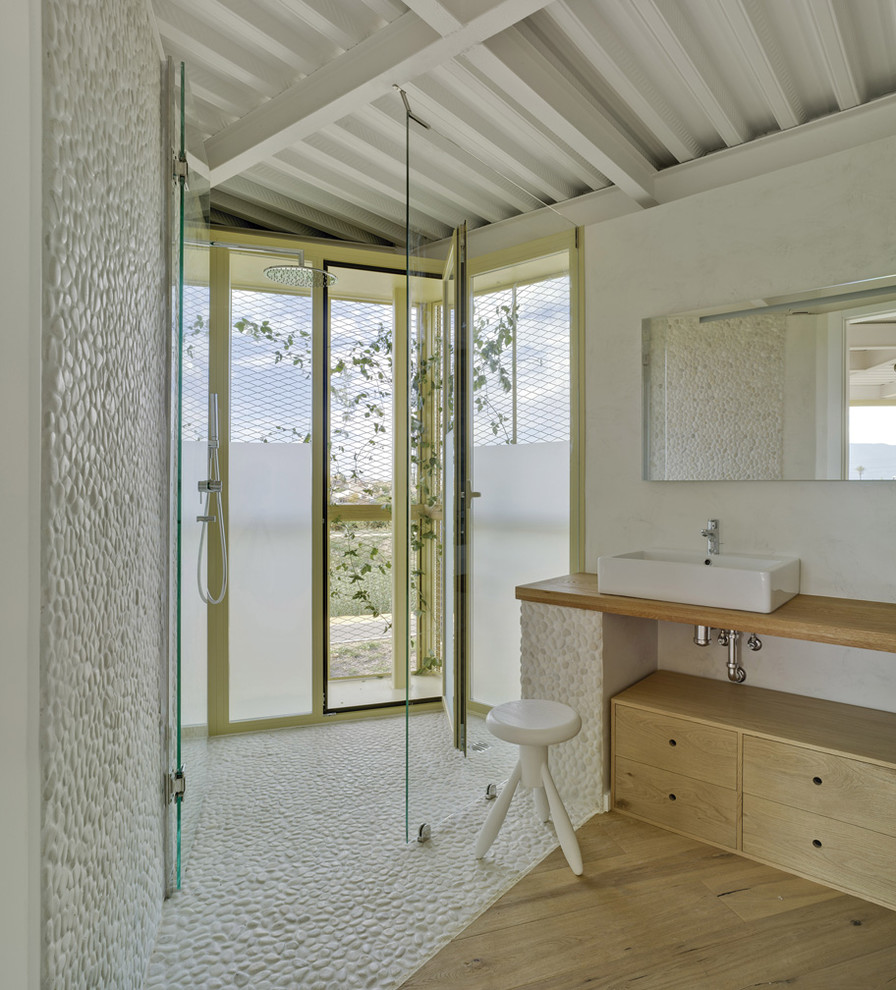 Inspiration för ett mellanstort industriellt badrum med dusch, med släta luckor, skåp i mellenmörkt trä, en kantlös dusch, vita väggar, mellanmörkt trägolv och ett fristående handfat