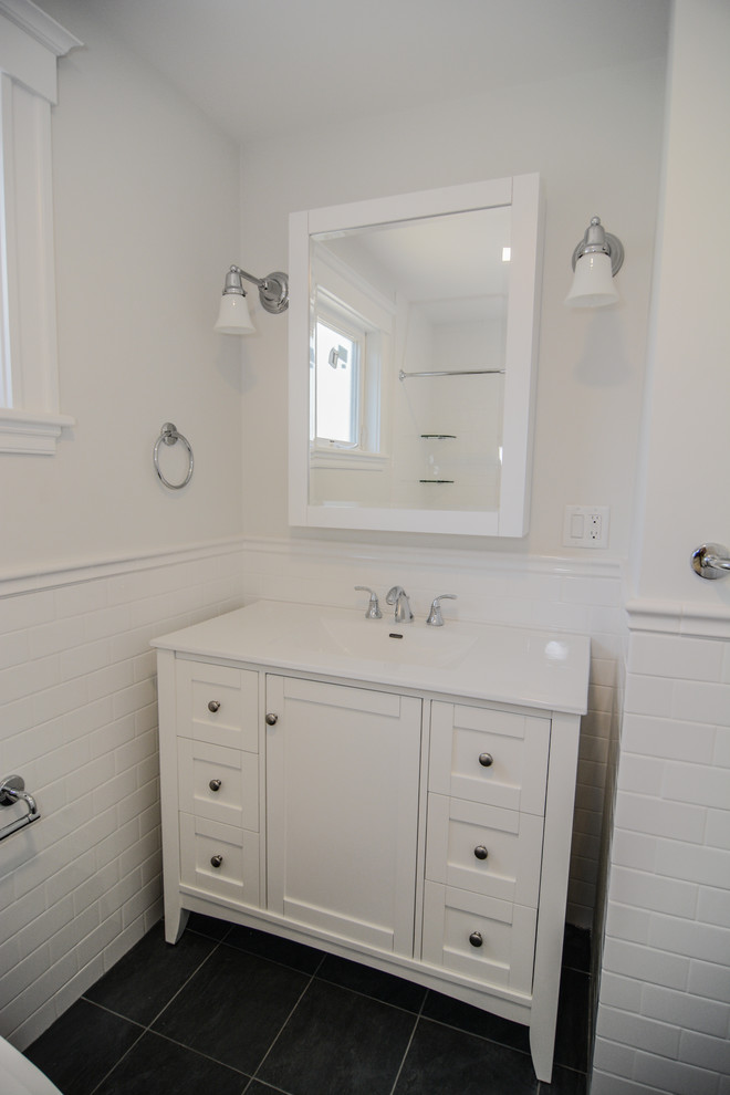 Cette image montre une salle de bain traditionnelle de taille moyenne avec un placard à porte shaker, des portes de placard blanches, une baignoire en alcôve, un combiné douche/baignoire, un bidet, un carrelage blanc, un carrelage métro, un mur blanc, un sol en carrelage de porcelaine et un lavabo intégré.