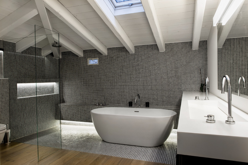 Inspiration for a large contemporary grey and white ensuite bathroom in Other with an integrated sink, a freestanding bath, a walk-in shower, a one-piece toilet, black walls, medium hardwood flooring, black and white tiles, ceramic tiles, solid surface worktops and an open shower.