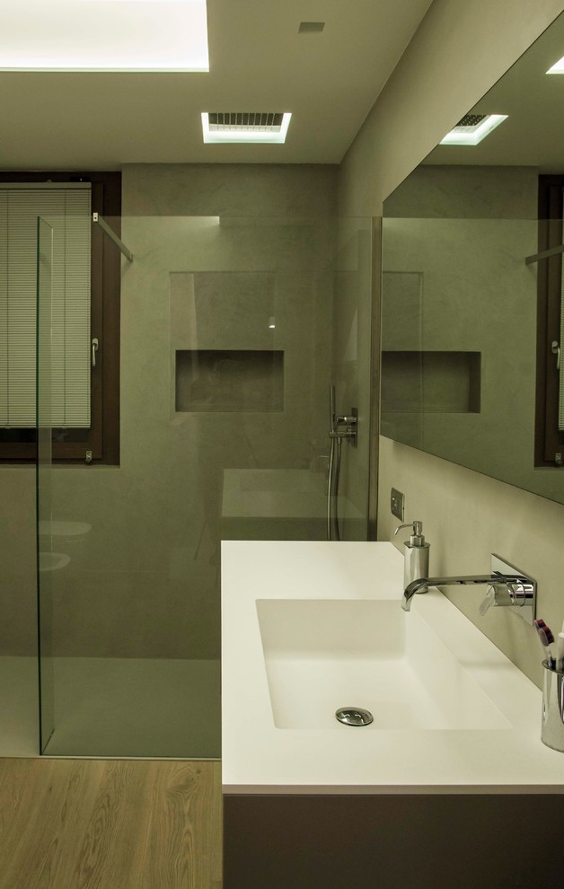 Ispirazione per una stanza da bagno con doccia minimalista di medie dimensioni con doccia a filo pavimento, WC a due pezzi, pareti grigie, parquet chiaro, lavabo integrato, pavimento marrone e doccia aperta