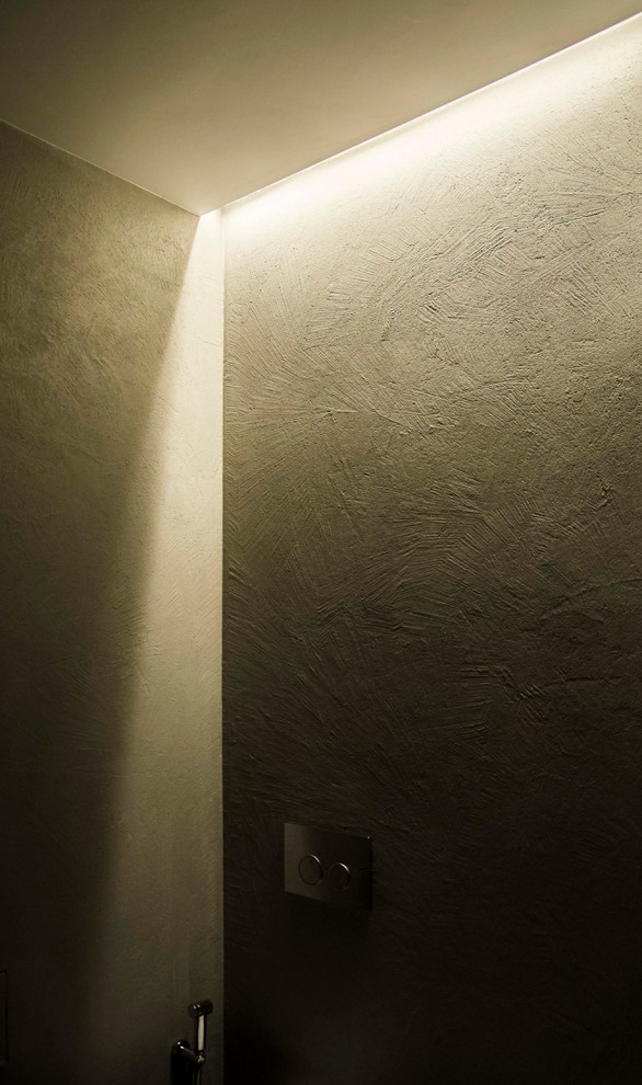 Modelo de cuarto de baño principal minimalista de tamaño medio con puertas de armario grises, sanitario de dos piezas, baldosas y/o azulejos grises, paredes grises, suelo de madera clara, lavabo con pedestal y suelo marrón