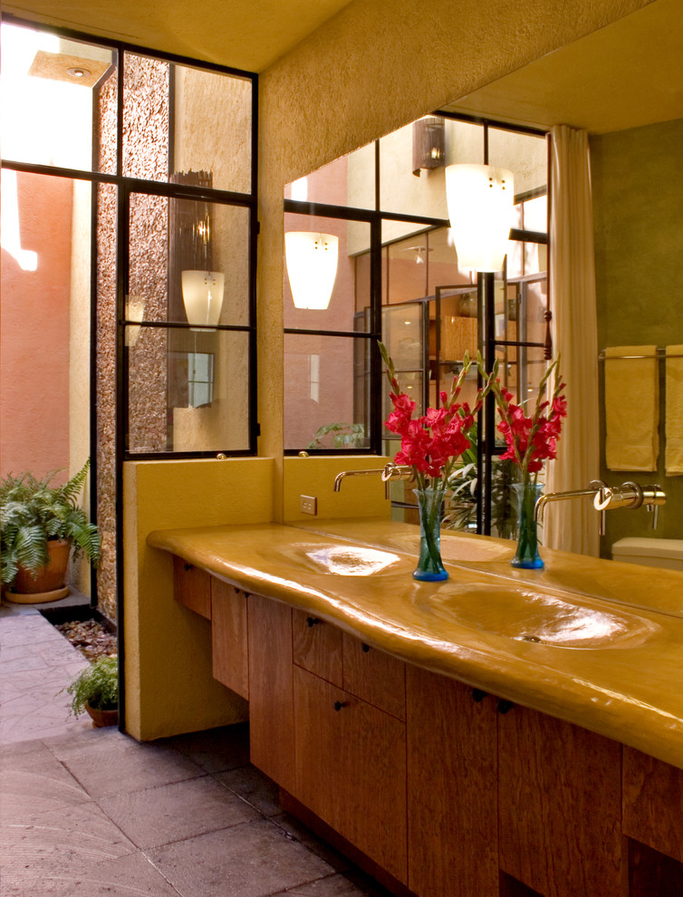 Immagine di una stanza da bagno minimalista con lavabo integrato, ante lisce, ante in legno scuro e top in legno