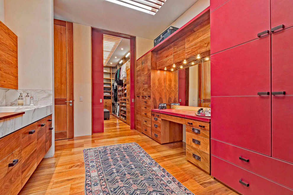 Idée de décoration pour une salle de bain design avec un lavabo intégré, un placard à porte plane, des portes de placard rouges, un mur beige et un sol en bois brun.