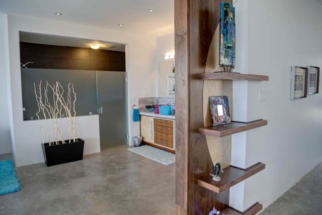 Foto på ett funkis en-suite badrum, med möbel-liknande, skåp i mellenmörkt trä, en kantlös dusch, grå kakel, porslinskakel, grå väggar, betonggolv, ett piedestal handfat och bänkskiva i betong