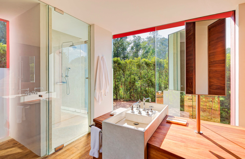 Diseño de cuarto de baño exótico con lavabo de seno grande, puertas de armario de madera en tonos medios, ducha empotrada, paredes blancas y suelo de madera en tonos medios