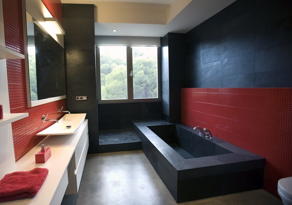 На фото: большая ванная комната в стиле модернизм с ванной в нише, настольной раковиной, белыми стенами, бетонным полом, серым полом, открытым душем, унитазом-моноблоком, черной плиткой, керамической плиткой, столешницей из плитки и открытым душем