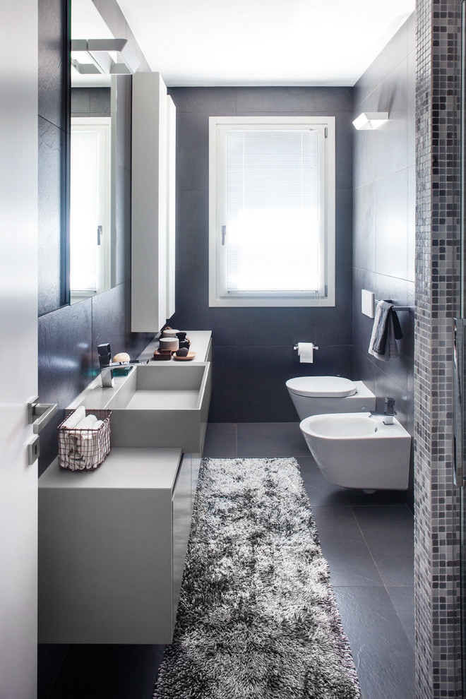 Exempel på ett litet modernt badrum med dusch, med släta luckor, ett avlångt handfat, grå skåp, en kantlös dusch, en vägghängd toalettstol, grå kakel, porslinskakel, grå väggar, klinkergolv i porslin, träbänkskiva, grått golv och dusch med gångjärnsdörr
