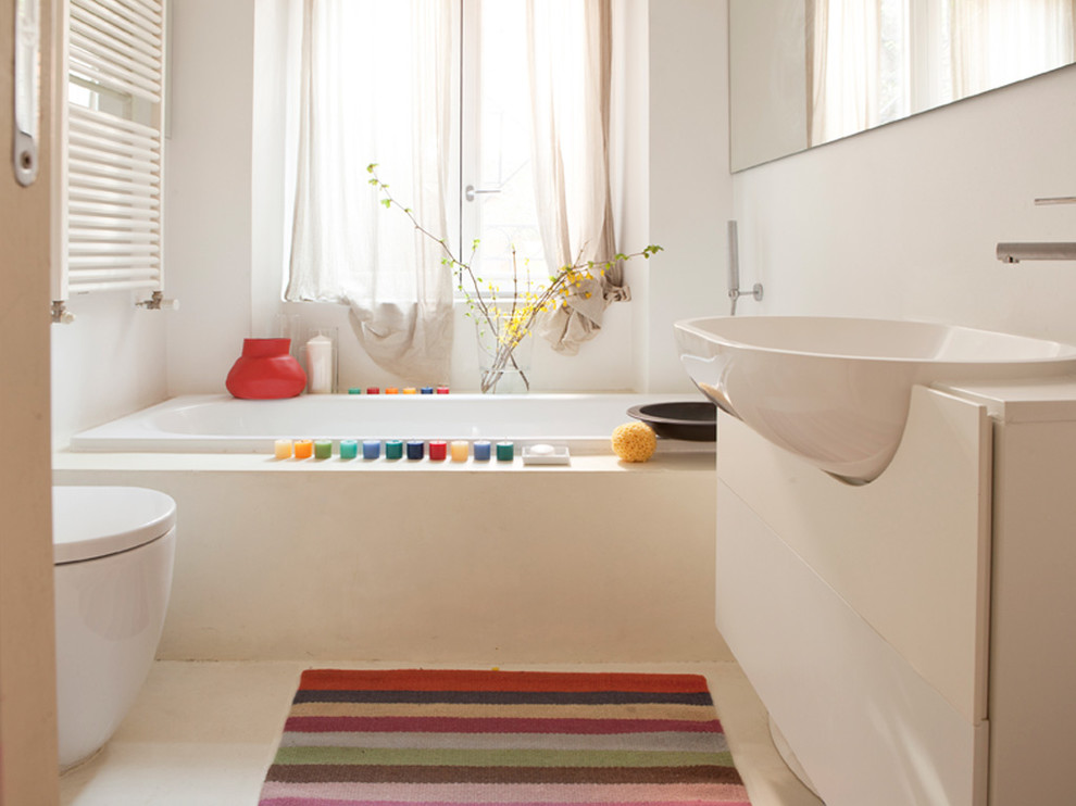 Foto di una piccola stanza da bagno minimal con ante lisce, ante bianche, vasca da incasso, WC monopezzo, pareti bianche e lavabo da incasso