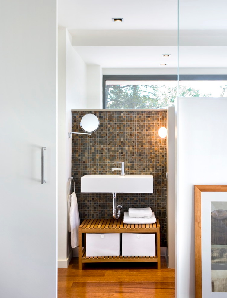 Réalisation d'une salle de bain design avec un mur multicolore et un sol en bois brun.