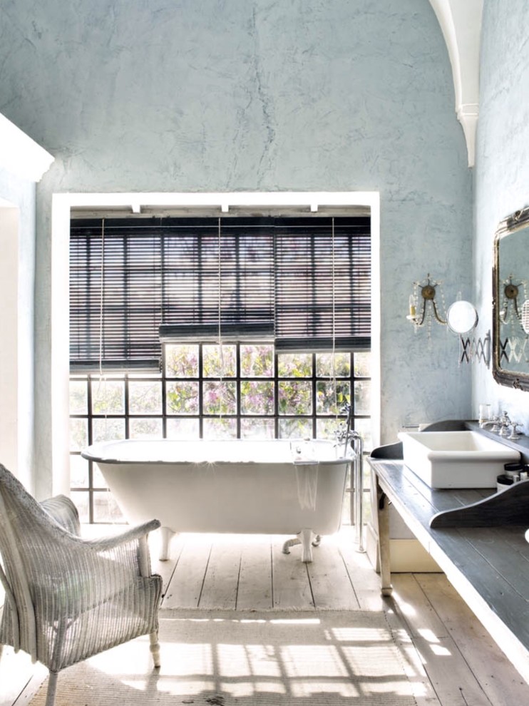 На фото: главная ванная комната среднего размера в стиле шебби-шик с настольной раковиной, столешницей из дерева, ванной на ножках, синими стенами, светлым паркетным полом, душем над ванной, серой столешницей и окном с