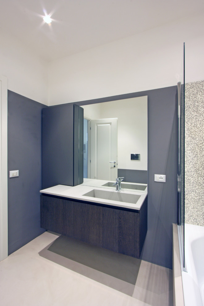 Example of a large trendy master gray tile and mosaic tile concrete floor drop-in bathtub design in Rome with a drop-in sink, furniture-like cabinets, dark wood cabinets, concrete countertops, a wall-mount toilet and gray walls