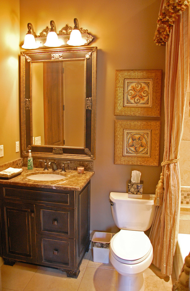 Photo of a small mediterranean shower room bathroom in Orlando with a submerged sink, a built-in bath, a shower/bath combination, a two-piece toilet, freestanding cabinets, granite worktops, beige tiles, ceramic tiles, brown walls, ceramic flooring and dark wood cabinets.
