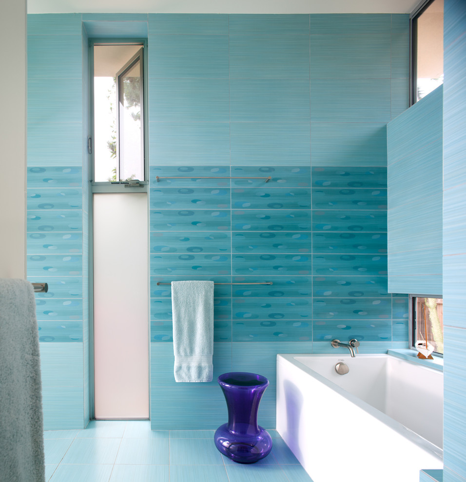 Modern inredning av ett badrum, med ett badkar i en alkov, blå kakel och blå väggar
