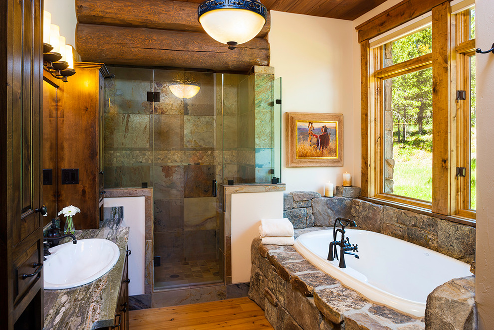Idée de décoration pour une grande douche en alcôve chalet en bois foncé avec un placard à porte shaker, une baignoire posée, un mur beige, un sol en bois brun et un lavabo posé.