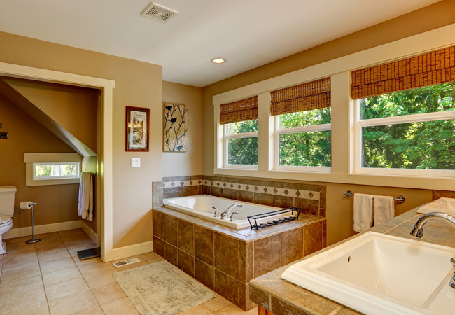 Example of a large tuscan master brown tile and ceramic tile ceramic tile and brown floor drop-in bathtub design in San Francisco with brown cabinets, brown walls, a drop-in sink, tile countertops and brown countertops