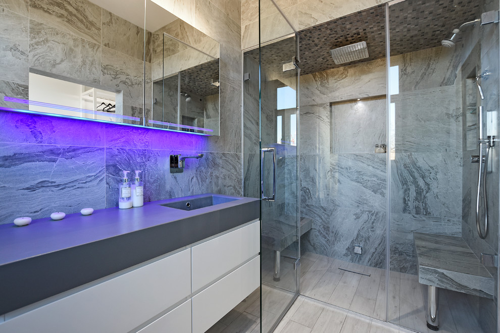 Wet room - large contemporary gray tile beige floor wet room idea in London with gray walls, a wall-mount sink and a hinged shower door
