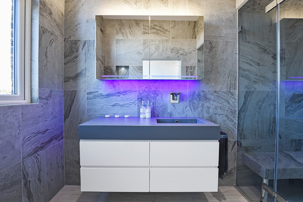 Cette photo montre une grande salle de bain tendance avec un espace douche bain, un carrelage gris, un mur gris, un lavabo suspendu, un sol beige et une cabine de douche à porte battante.