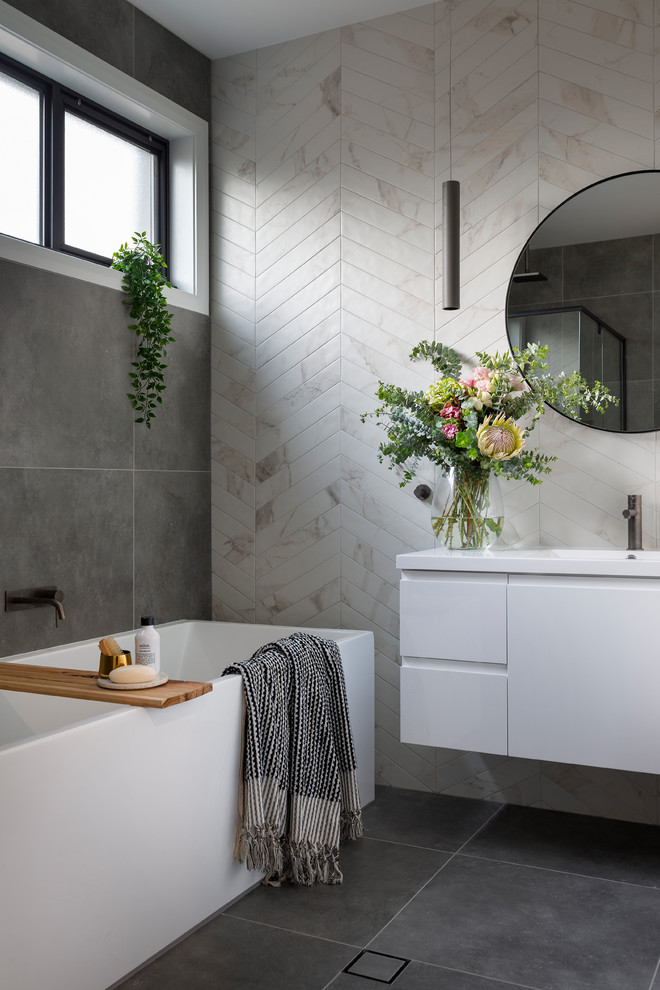 Modernes Badezimmer mit weißen Schränken, grauen Fliesen, beigen Fliesen, Porzellanfliesen, Porzellan-Bodenfliesen, integriertem Waschbecken, grauem Boden, flächenbündigen Schrankfronten, Badewanne in Nische und weißer Waschtischplatte in Canberra - Queanbeyan