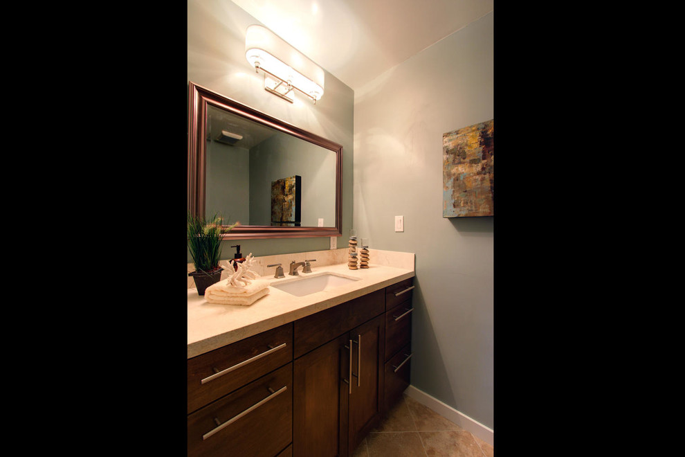Immagine di una stanza da bagno contemporanea con lavabo sottopiano, ante in stile shaker, ante in legno scuro, top in pietra calcarea, piastrelle beige e piastrelle in pietra