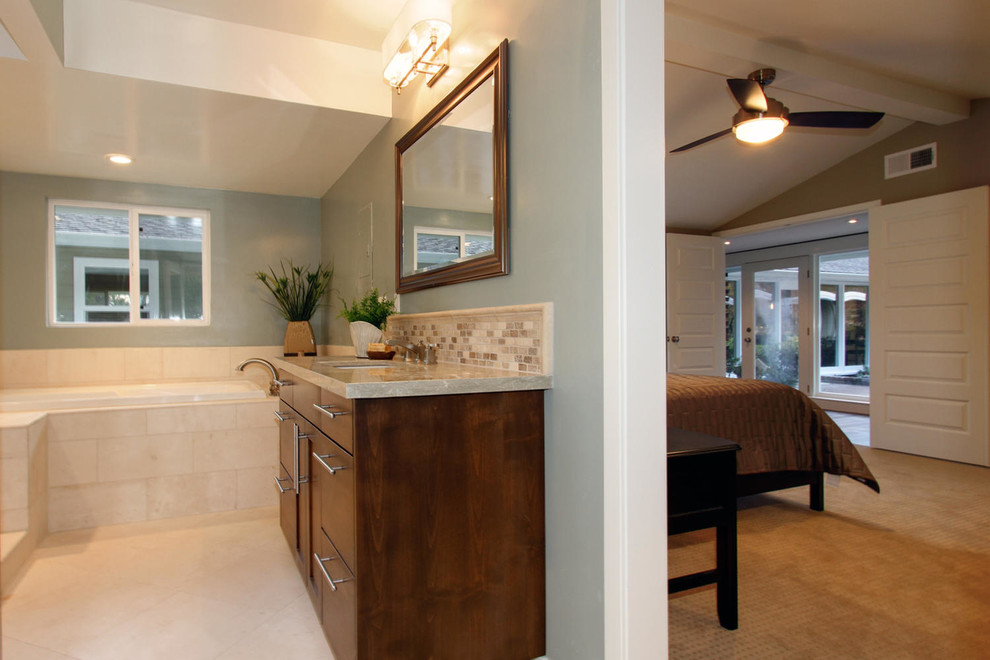 Foto de cuarto de baño actual con lavabo bajoencimera, armarios con paneles lisos, encimera de piedra caliza, bañera encastrada y baldosas y/o azulejos beige
