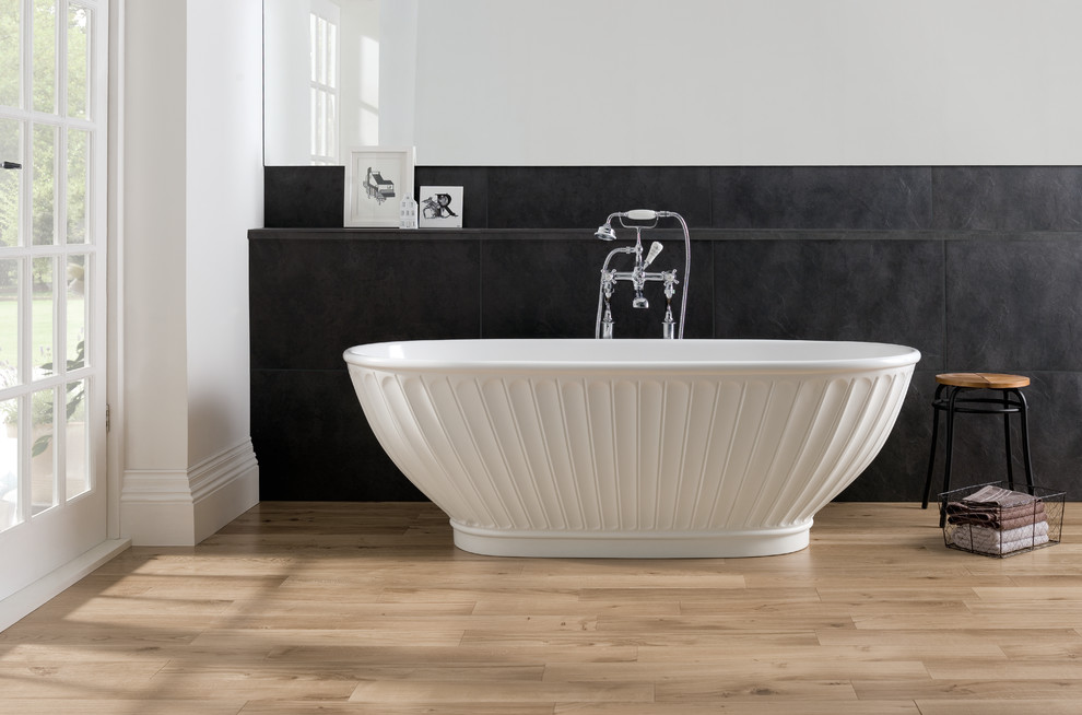 Immagine di una stanza da bagno minimalista con vasca freestanding, piastrelle grigie, piastrelle in gres porcellanato, pareti bianche e parquet chiaro