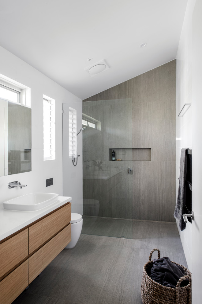 Foto di una stanza da bagno minimal con ante lisce, ante in legno scuro, doccia alcova, piastrelle grigie, lavabo da incasso, pavimento grigio e top bianco