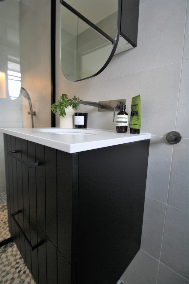 Photo of a medium sized eclectic bathroom in Sydney with black cabinets, a one-piece toilet, grey tiles, porcelain tiles, terrazzo flooring, solid surface worktops, white worktops, a single sink and a floating vanity unit.