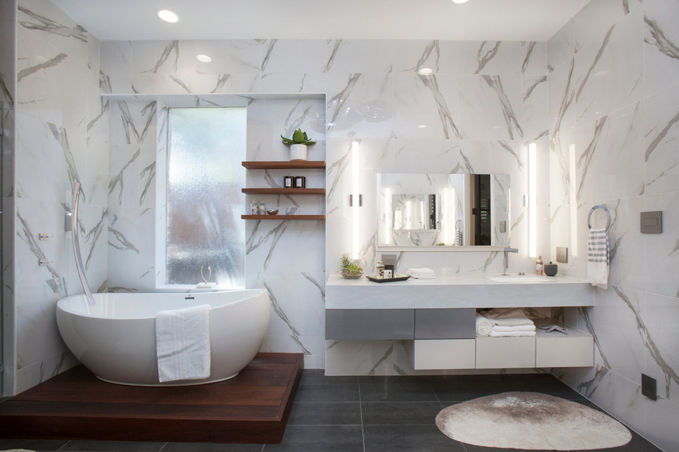Источник вдохновения для домашнего уюта: большая главная ванная комната в современном стиле с плоскими фасадами, белыми фасадами, гидромассажной ванной, унитазом-моноблоком, серой плиткой, керамогранитной плиткой, накладной раковиной, столешницей из известняка, душем в нише, белыми стенами, бетонным полом, серым полом и серой столешницей