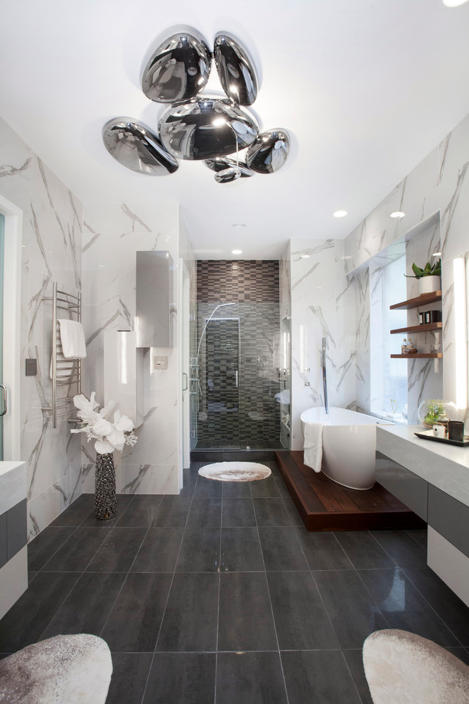 Свежая идея для дизайна: большая главная ванная комната в современном стиле с плоскими фасадами, белыми фасадами, гидромассажной ванной, унитазом-моноблоком, серой плиткой, керамогранитной плиткой, накладной раковиной, столешницей из известняка, душем в нише, белыми стенами, полом из керамической плитки, черным полом, душем с распашными дверями и серой столешницей - отличное фото интерьера