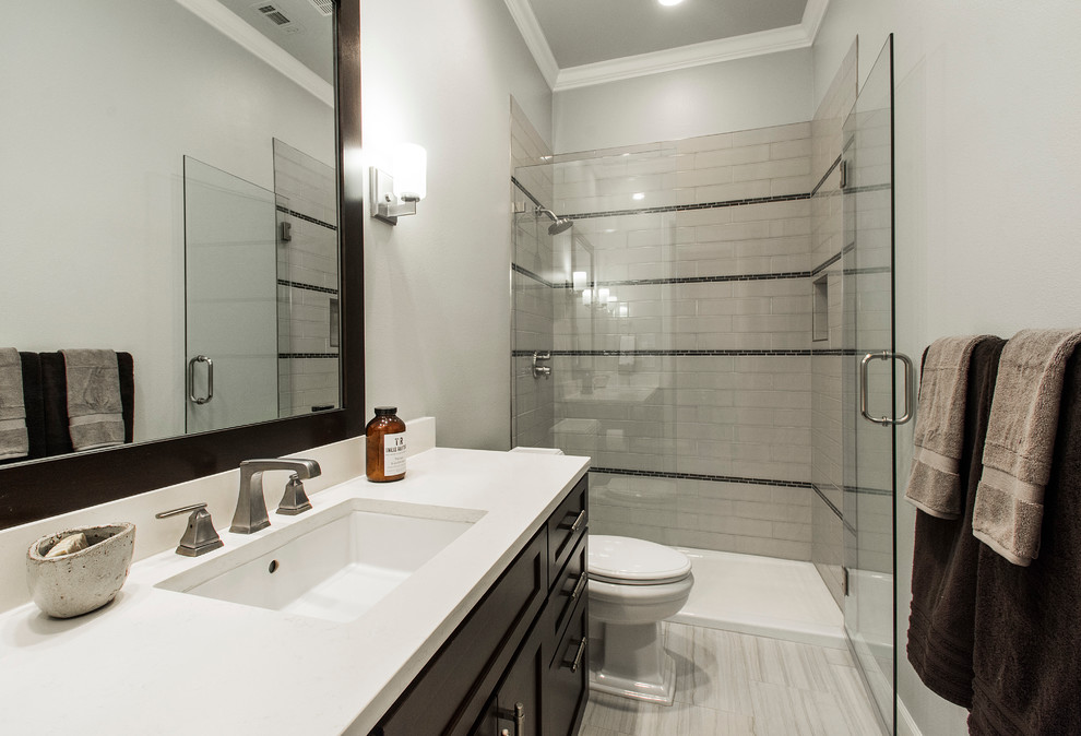 Medium sized classic shower room bathroom in Dallas with shaker cabinets, dark wood cabinets, a shower/bath combination, a one-piece toilet, black and white tiles, ceramic tiles, grey walls, porcelain flooring, a submerged sink and solid surface worktops.