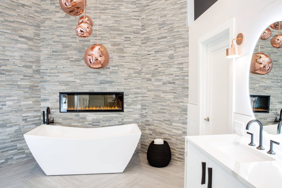 На фото: огромная главная ванная комната в стиле модернизм с плоскими фасадами, белыми фасадами, отдельно стоящей ванной, угловым душем, унитазом-моноблоком, белой плиткой, керамической плиткой, белыми стенами, полом из керамогранита, врезной раковиной, столешницей из искусственного кварца, серым полом, душем с распашными дверями и белой столешницей с