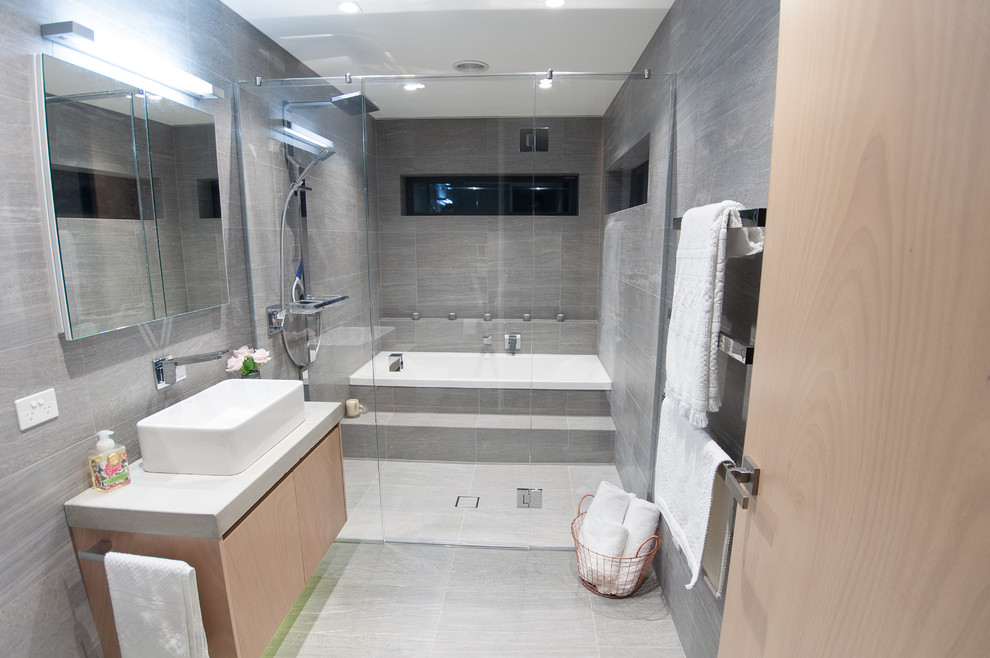 Idee per una stanza da bagno contemporanea di medie dimensioni con vasca da incasso, doccia aperta, WC sospeso, piastrelle grigie, piastrelle in pietra, pareti grigie, lavabo rettangolare e top in cemento