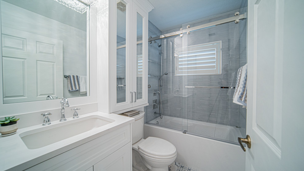Inredning av ett klassiskt litet vit vitt badrum med dusch, med skåp i shakerstil, vita skåp, ett badkar i en alkov, en toalettstol med separat cisternkåpa, vita väggar, klinkergolv i porslin, ett undermonterad handfat, bänkskiva i kvartsit och blått golv