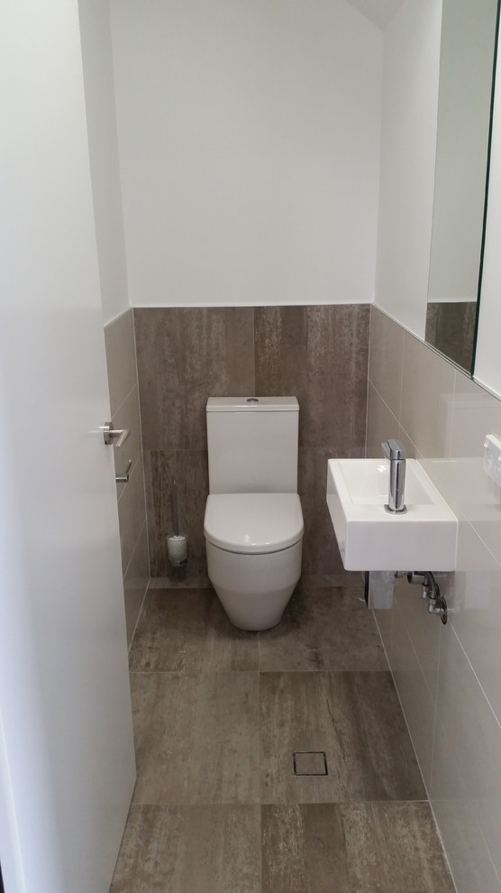 Cette photo montre un WC et toilettes moderne de taille moyenne avec un lavabo suspendu, un carrelage blanc, des carreaux de porcelaine, un mur gris et un sol en carrelage de porcelaine.