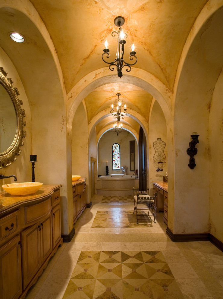 Ejemplo de cuarto de baño mediterráneo con lavabo sobreencimera, armarios con paneles con relieve, puertas de armario de madera oscura y paredes beige