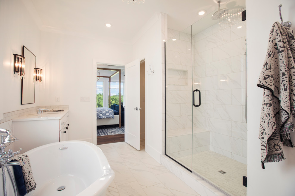 Photo of a large traditional ensuite bathroom in Louisville with recessed-panel cabinets, white cabinets, a freestanding bath, an alcove shower, a one-piece toilet, white tiles, marble tiles, white walls, marble flooring, quartz worktops, white floors, a hinged door, white worktops and a submerged sink.