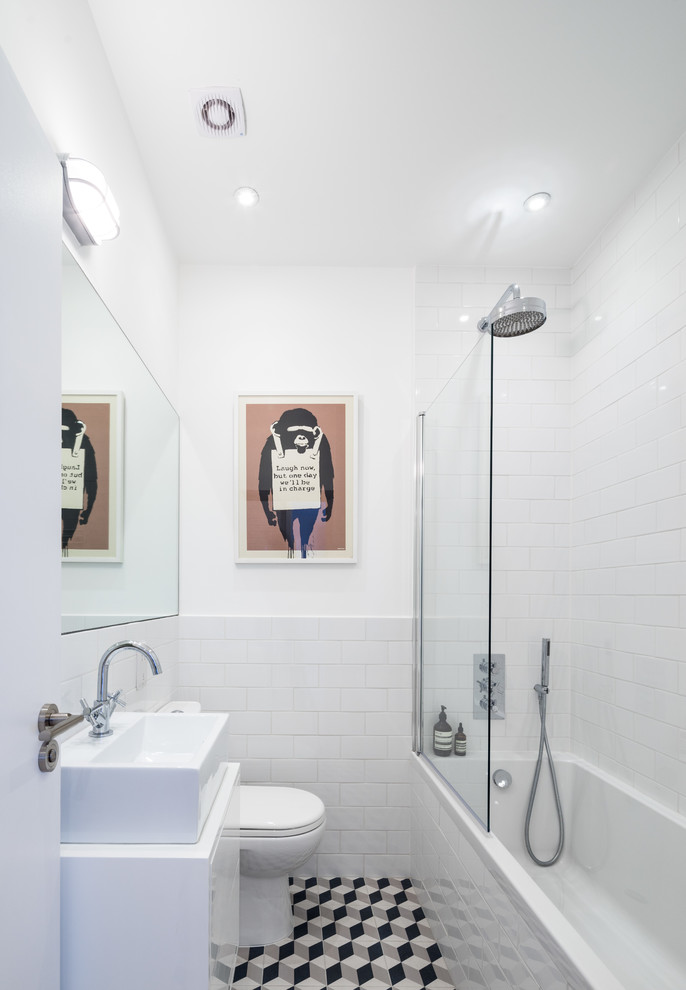 Idee per una stanza da bagno design con lavabo a bacinella, ante lisce, ante bianche, vasca da incasso, vasca/doccia, piastrelle bianche, piastrelle diamantate e pavimento multicolore