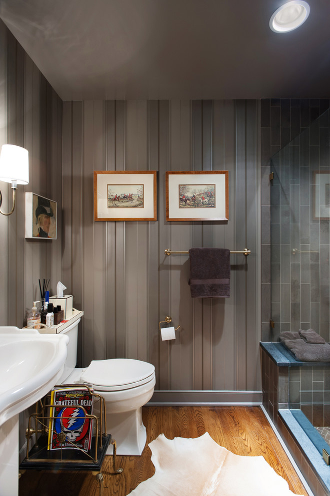 Diseño de cuarto de baño tradicional con sanitario de dos piezas, paredes grises, suelo de madera en tonos medios y lavabo con pedestal