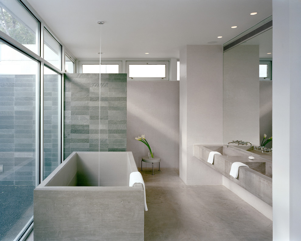 Modernes Badezimmer En Suite mit freistehender Badewanne, bodengleicher Dusche, Betonboden, integriertem Waschbecken, Beton-Waschbecken/Waschtisch und Steinwänden in New York