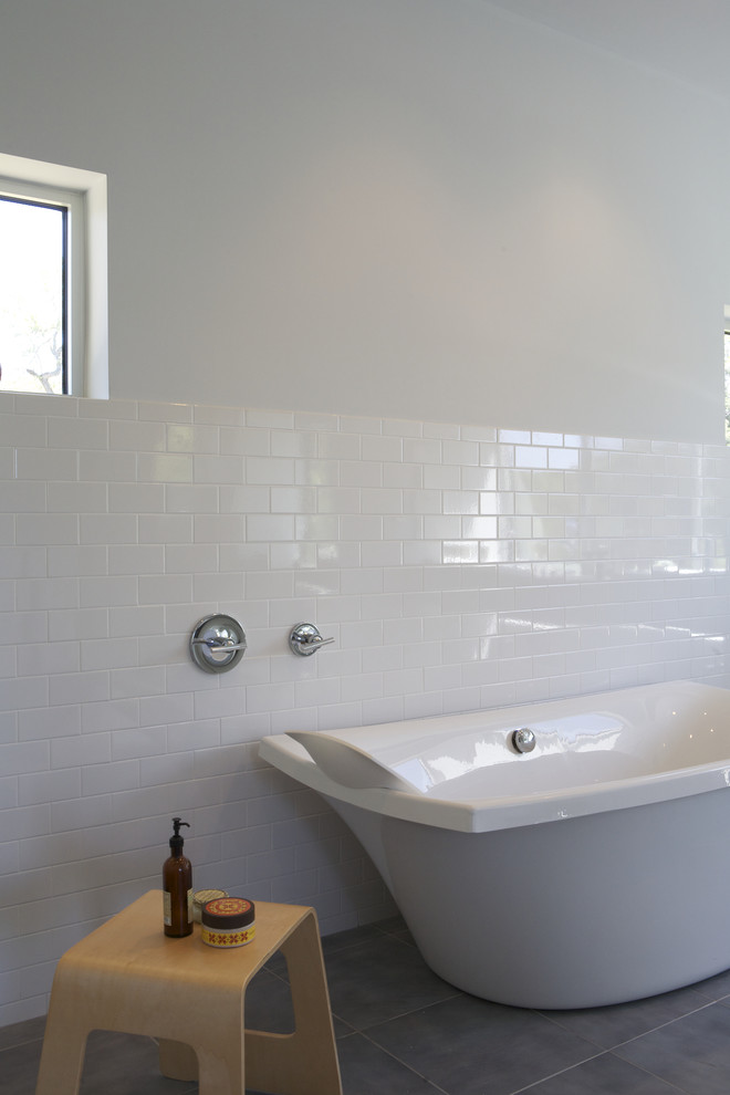Inredning av ett modernt badrum, med ett fristående badkar, tunnelbanekakel och grått golv