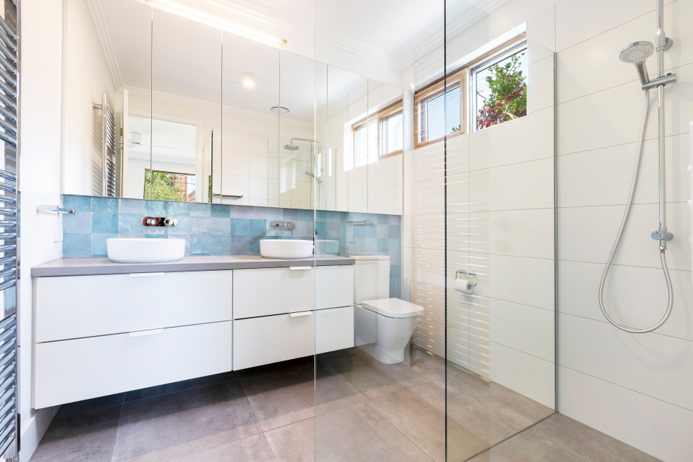 Пример оригинального дизайна: ванная комната в современном стиле с плоскими фасадами, белыми фасадами, душем без бортиков, синей плиткой, душевой кабиной, настольной раковиной, серым полом, серой столешницей, тумбой под две раковины и подвесной тумбой