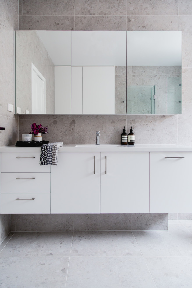 Immagine di una stanza da bagno padronale design di medie dimensioni con piastrelle beige, pavimento con piastrelle in ceramica, ante lisce, ante bianche, pareti beige e lavabo integrato
