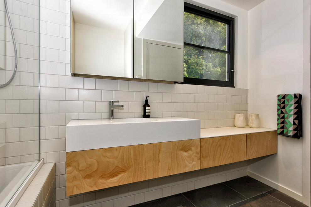 Exemple d'une petite salle de bain tendance en bois clair pour enfant avec un combiné douche/baignoire, un carrelage blanc, un carrelage métro, un lavabo encastré, un plan de toilette en quartz modifié et une cabine de douche à porte battante.