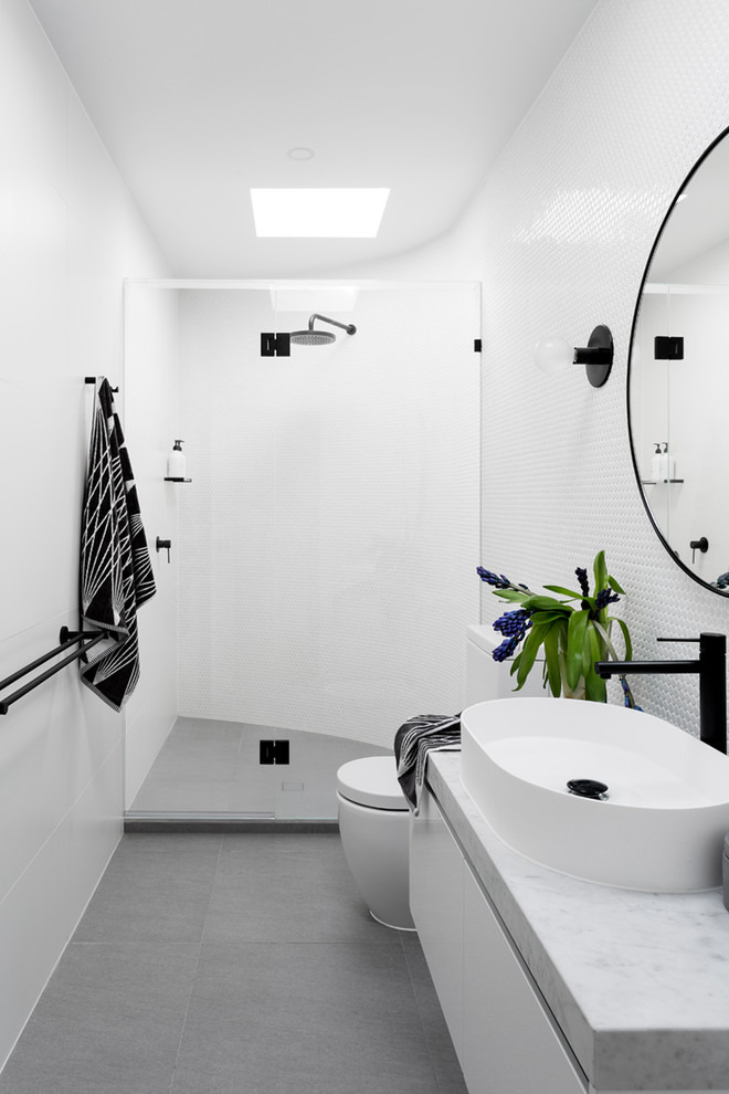 Inspiration for a mid-sized contemporary 3/4 white tile and mosaic tile porcelain tile and gray floor alcove shower remodel in Melbourne with flat-panel cabinets, white cabinets, a one-piece toilet, white walls, a vessel sink and marble countertops