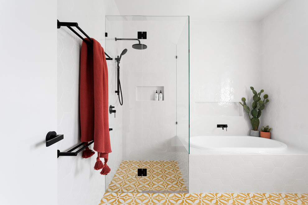 Inredning av ett modernt mellanstort badrum med dusch, med ett platsbyggt badkar, en hörndusch, vit kakel, gult golv, dusch med gångjärnsdörr, porslinskakel, cementgolv, släta luckor, vita skåp och vita väggar