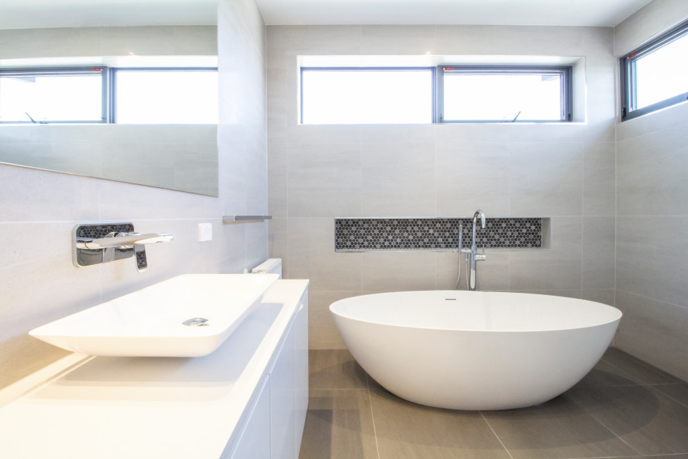 Modern inredning av ett stort vit vitt en-suite badrum, med luckor med lamellpanel, vita skåp, ett fristående badkar, en öppen dusch, en bidé, beige kakel, cementkakel, cementgolv, ett fristående handfat, bänkskiva i betong, grått golv och med dusch som är öppen
