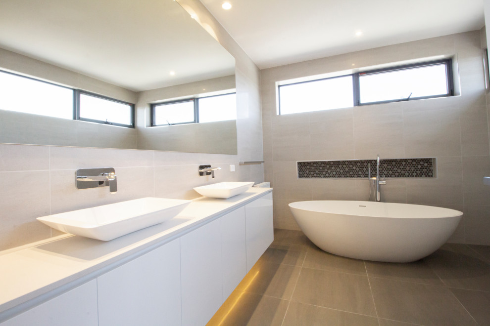Exempel på ett stort modernt vit vitt en-suite badrum, med luckor med lamellpanel, vita skåp, ett fristående badkar, en öppen dusch, en bidé, beige kakel, cementkakel, cementgolv, ett fristående handfat, bänkskiva i betong, grått golv och med dusch som är öppen